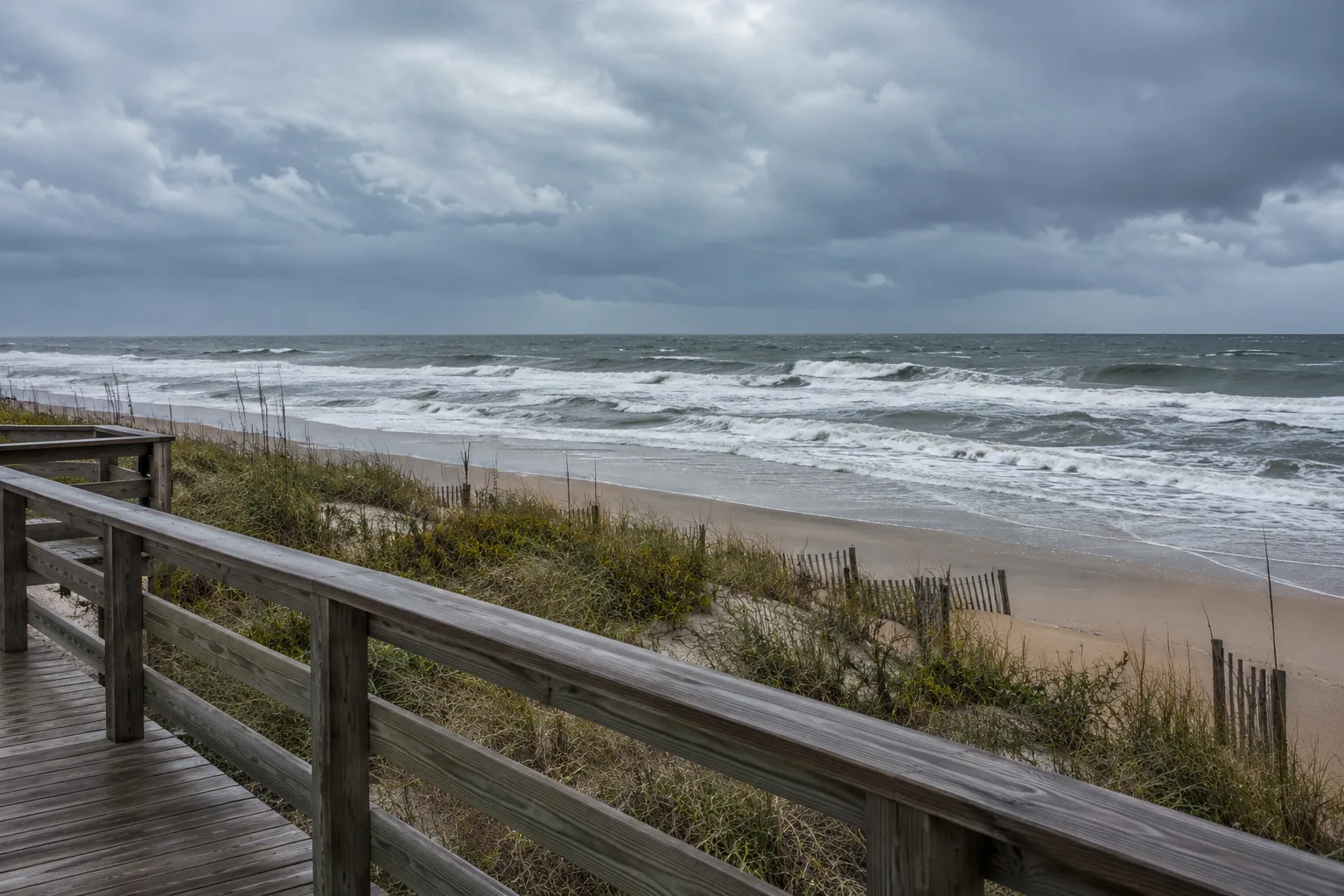 Choppy surf viewed from behind a boardwalk railing.
